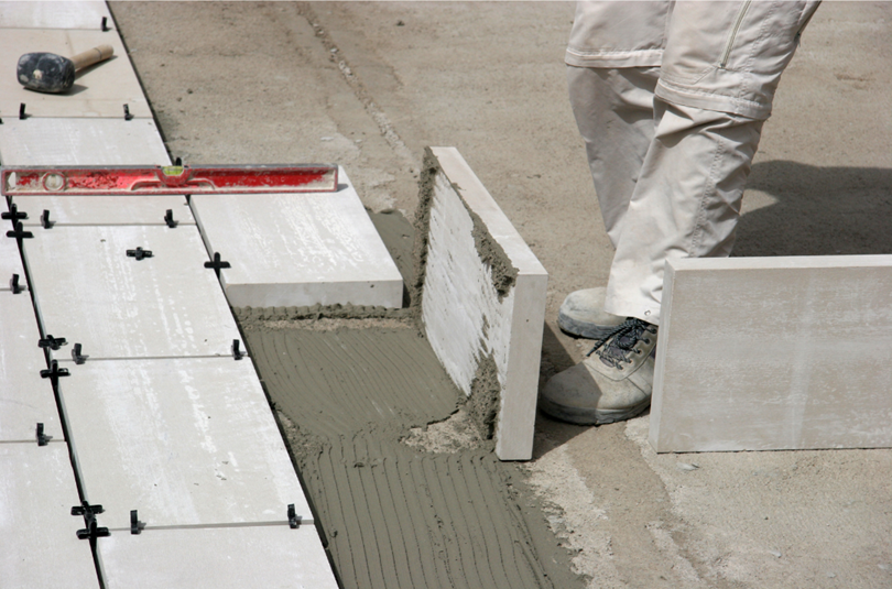 A tiler laying very thick marble tiles.